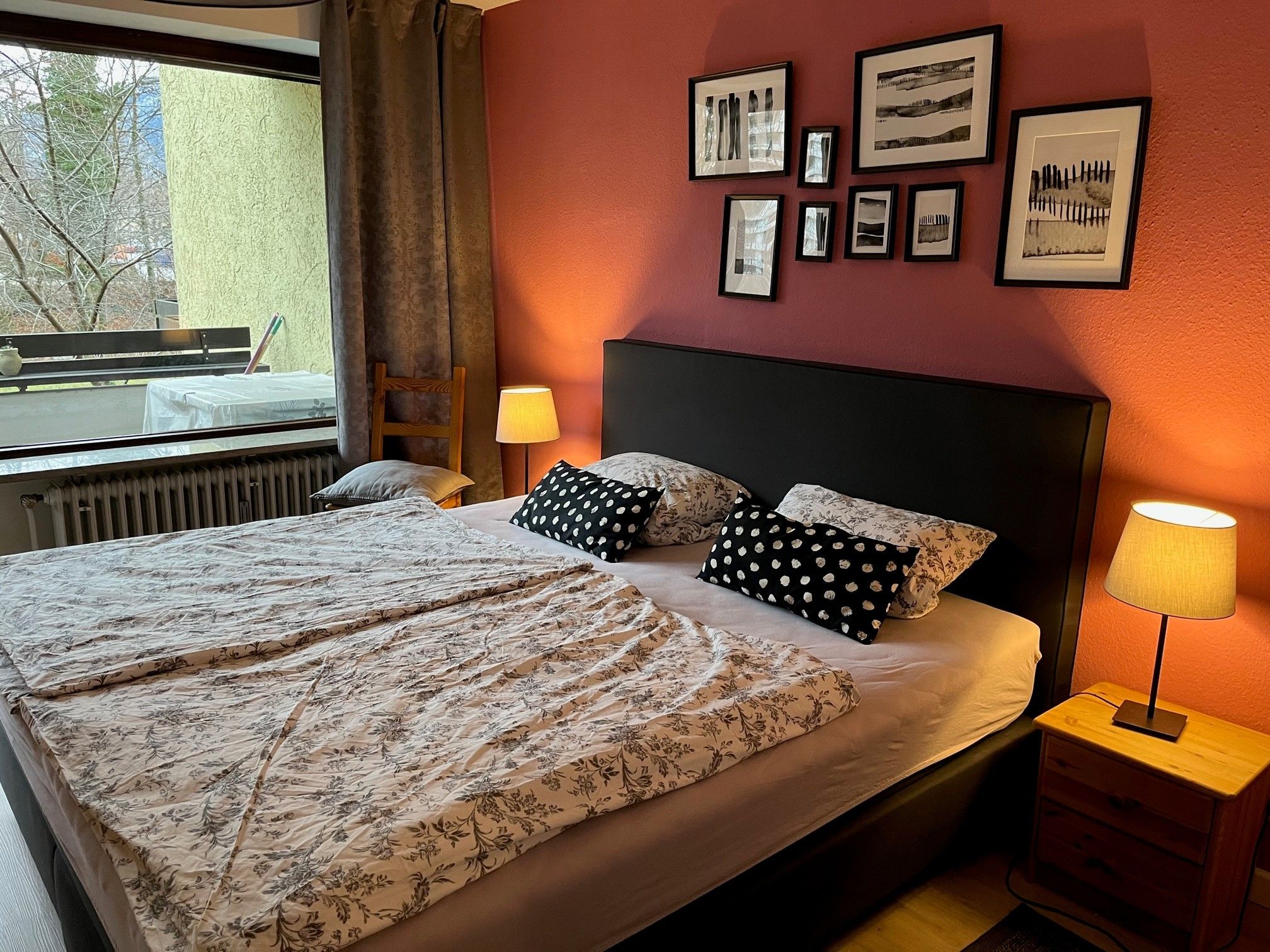 Ein Hotelzimmer mit einem Bett, zwei Nachttischlampen, einem Vorhangfenster und mehreren gerahmten Bildern an der Wand.