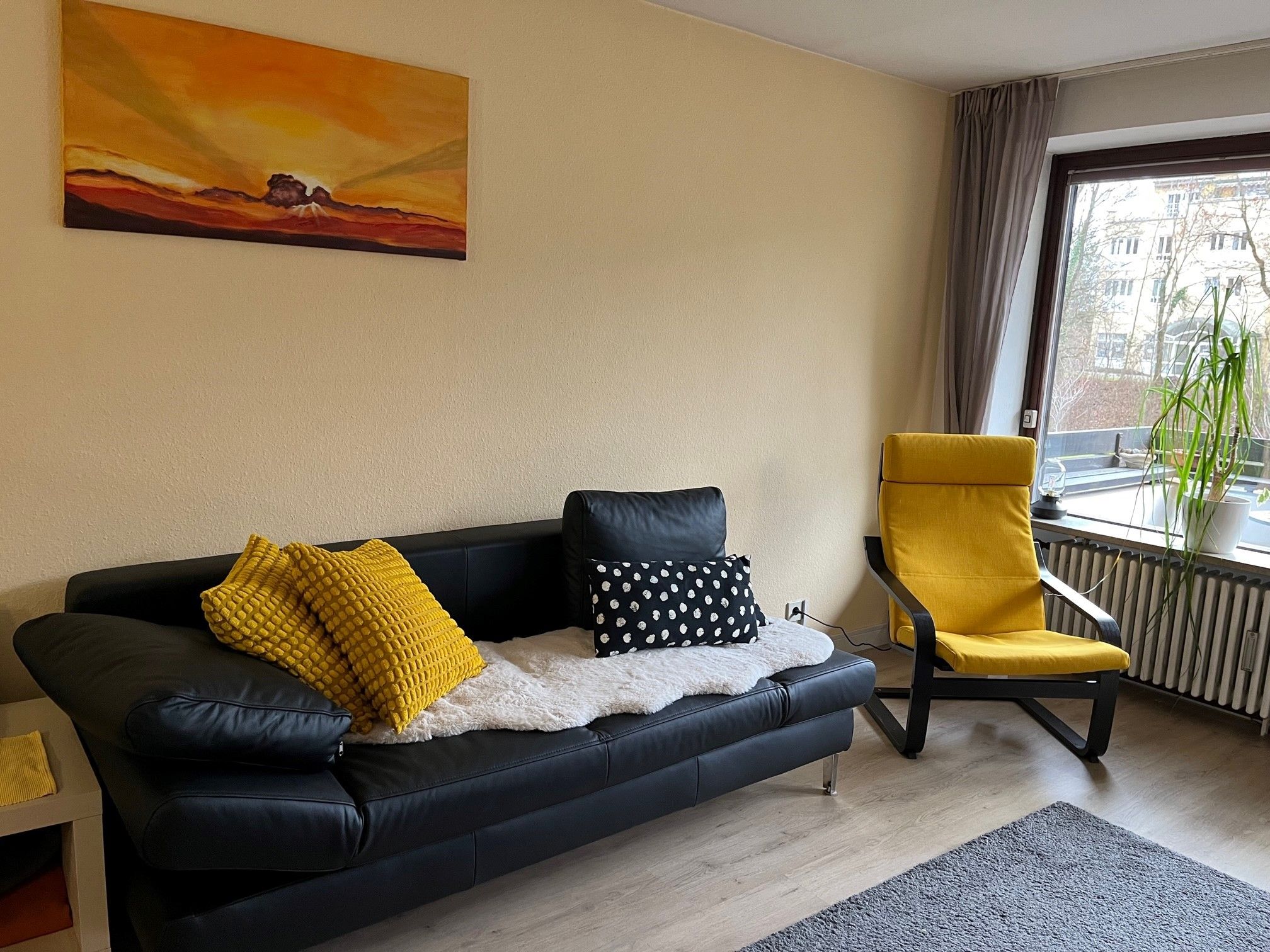 Ein modernes Wohnzimmer mit einer schwarzen Ledersofa, einem gelben Sessel und einem Gemälde an der Wand.