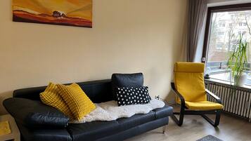 Ein modernes Wohnzimmer mit einer schwarzen Ledersofa, einem gelben Sessel und einem Gemälde an der Wand.