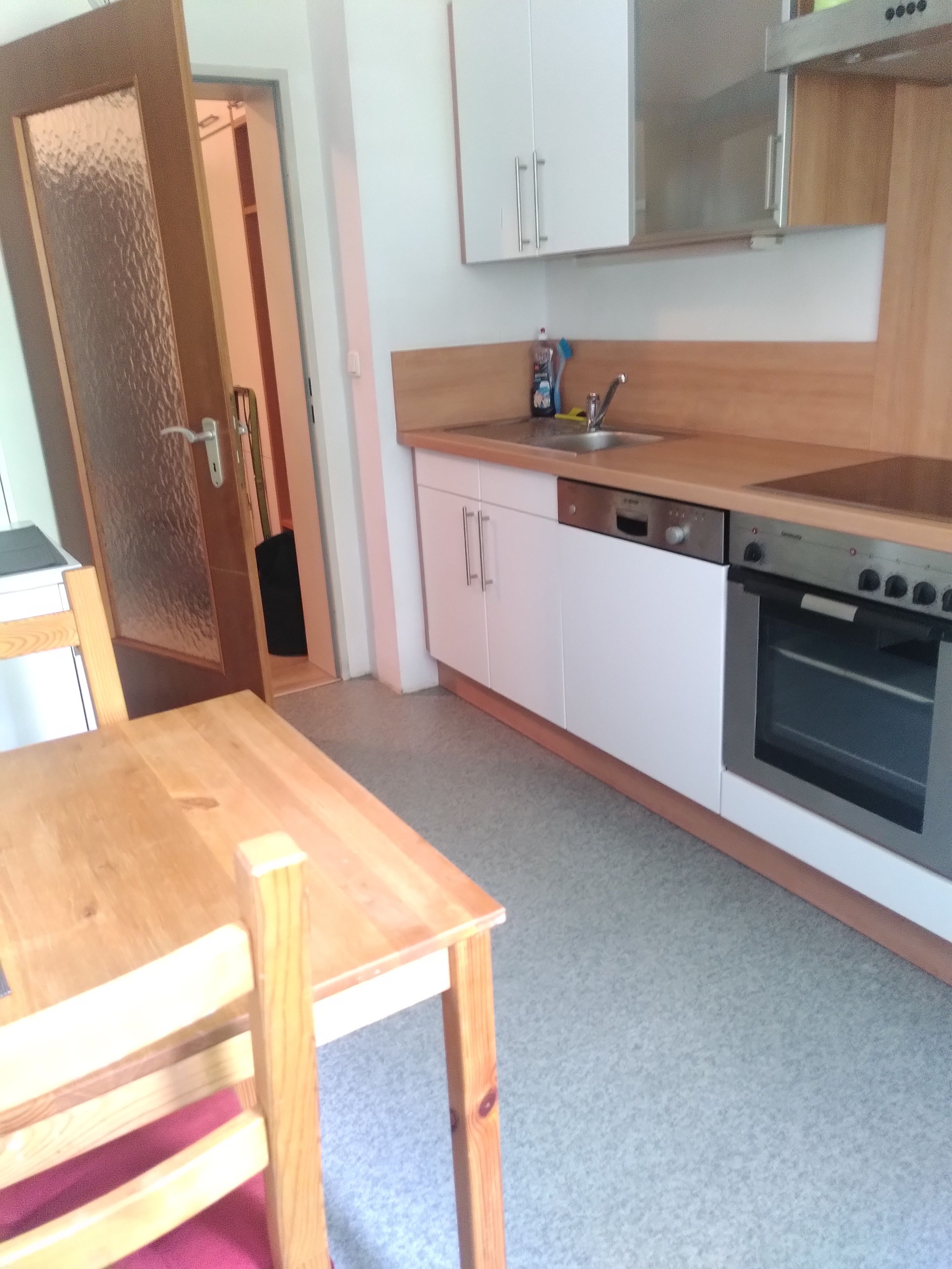 A kitchen with a wooden table, white cabinets, and a built-in oven.