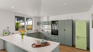 A modern kitchen with a central island, a built-in oven, and a green refrigerator. - Quat Quatta - Point Lonsdale (Point Lonsdale)
