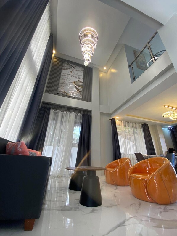 A spacious living area with a high ceiling, a chandelier, and modern furniture.