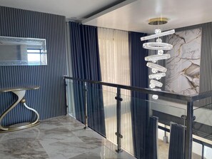 A modern interior with a marble floor, a glass railing, and a decorative wall panel.