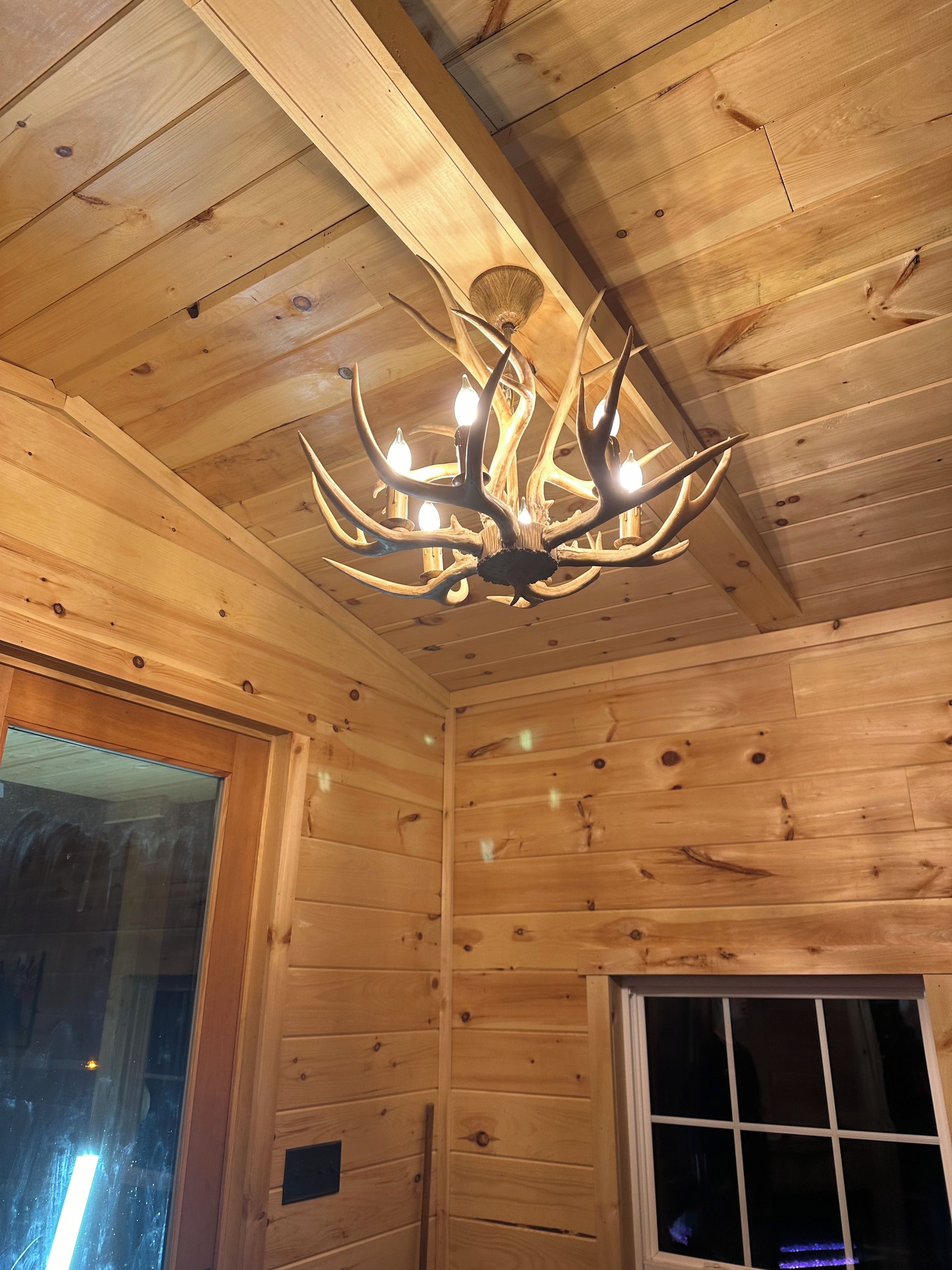 A wooden interior with a chandelier and a window.