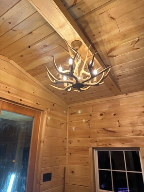 A wooden interior with a chandelier and a window.