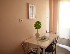 A dining table with chairs, a vase with a plant, and a framed picture on the wall. - Spacious 1BR Apartment|, 3-min Walk to Sykies Beach (Chalkida)