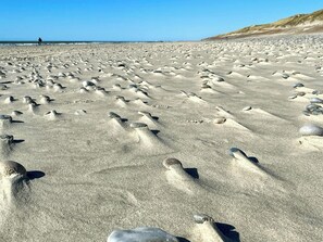 A beach with numerous footprints and rocks scattered across the sand. - Family summer house on the dune with sea views (Ringkøbing)