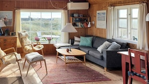 A cozy room with a sofa, chairs, a table, and a view of the outdoors. - Family summer house on the dune with sea views (Ringkøbing)