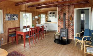 Een houten interieur met een eethoek, keuken en open haard.