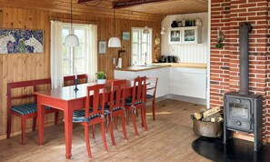 A wooden interior with a dining table, chairs, a stove, and a kitchen area. - Family summer house on the dune with sea views (Ringkøbing)