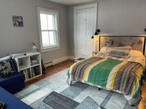 A bedroom with a bed, a desk, a chair, and a window.