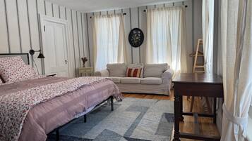 A bedroom with a bed, a sofa, a small table, and a ladder.