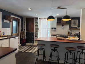 A kitchen with a central island, bar stools, and pendant lighting.