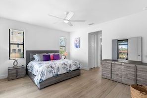 A bedroom with a bed, bedside tables, a ceiling fan, a window with blinds, a door, and a view of the outdoors. - Waterfront Retreat - Pool, Dock, 3 Min to Bonita Beach (Bonita Springs)