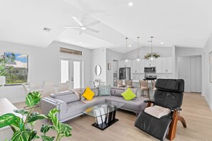 A modern living room with a sectional sofa, a black leather chair, and a glass coffee table. - Waterfront Retreat - Pool, Dock, 3 Min to Bonita Beach (Bonita Springs)