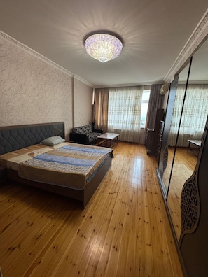 Un dormitorio con cama, sofá, cómoda y un espejo grande.