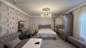 Un dormitorio con una cama grande, un sofá, una mesa y una araña.