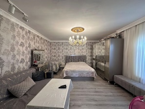 Un dormitorio con una cama grande, un sofá, una mesa y una araña.