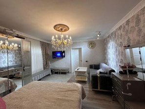 Ein Hotelzimmer mit einem Bett, einer Couch, einem Fernseher, einer Kandelaber und einem Schminktisch.