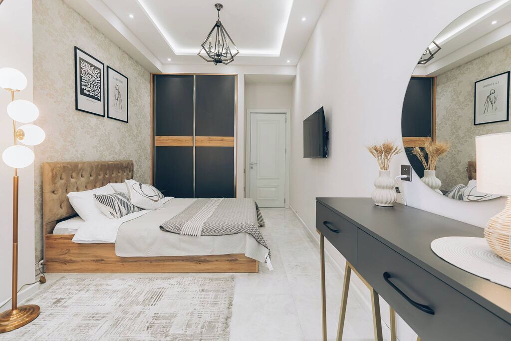 Une chambre à coucher moderne avec un lit, une table de chevet et un grand miroir.