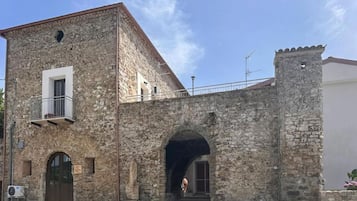 A stone building with a balcony, an arched entrance, and a small tower.