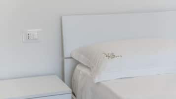 A white bed with a simple headboard and a small bedside table.