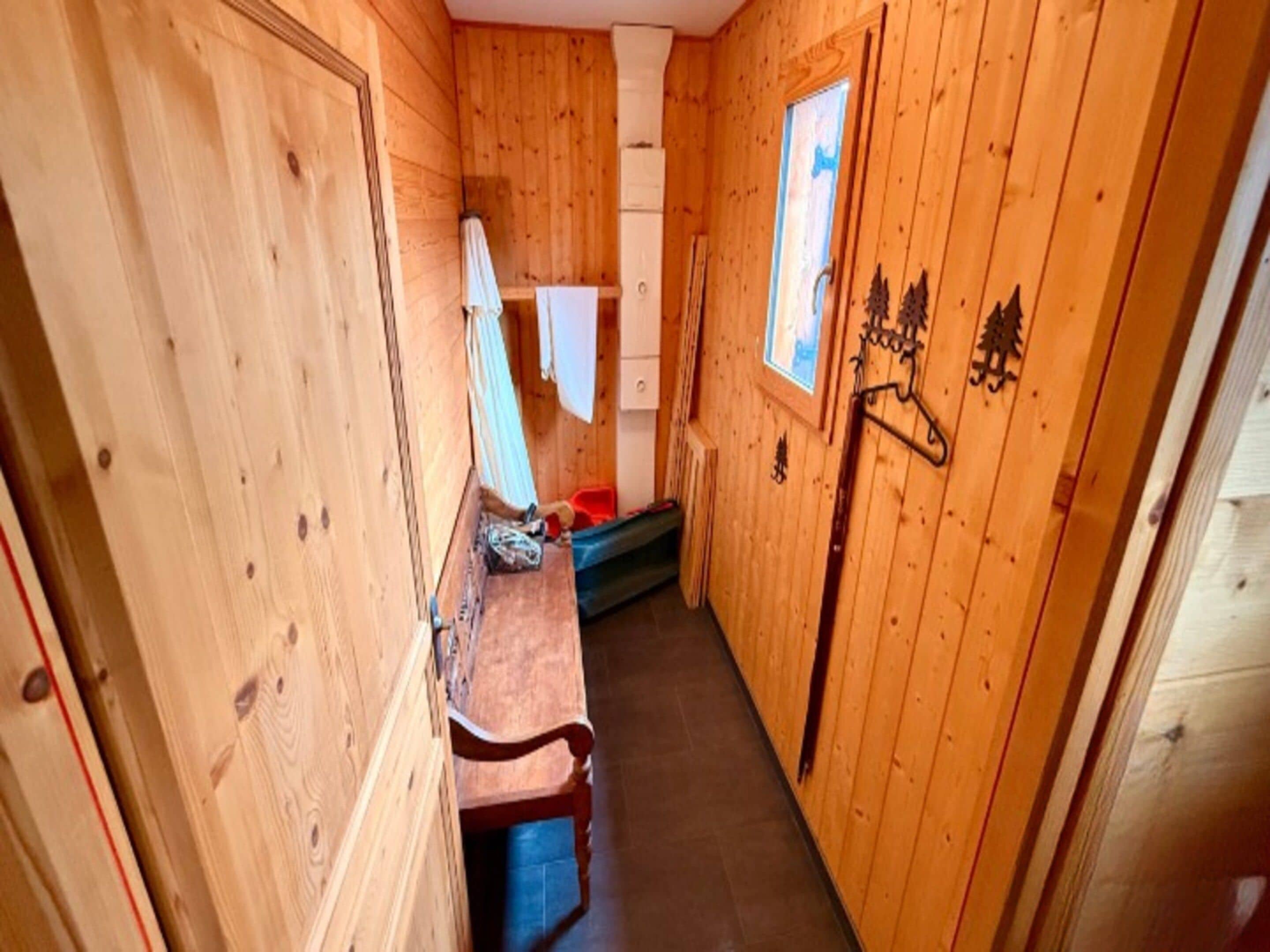 A narrow hallway with wooden walls, a bench, and a window with a view.