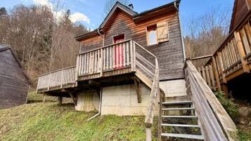 A wooden house with a balcony and a staircase leading to the entrance.