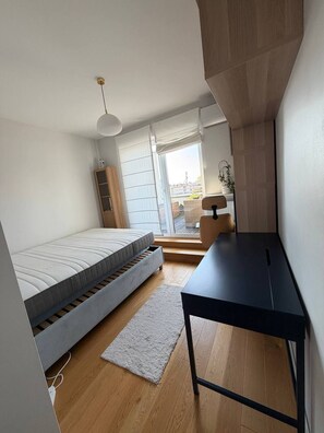 A bedroom with a bed, a desk, a chair, and a view through a window. - Lumina 2BR Apt w/ Terrace & Parking (Warszawa)