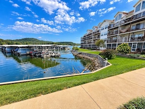 A waterfront property with a dock, a grassy area, and a multi-story building with balconies. - Big Niangua Getaway - Lake View (Camdenton)