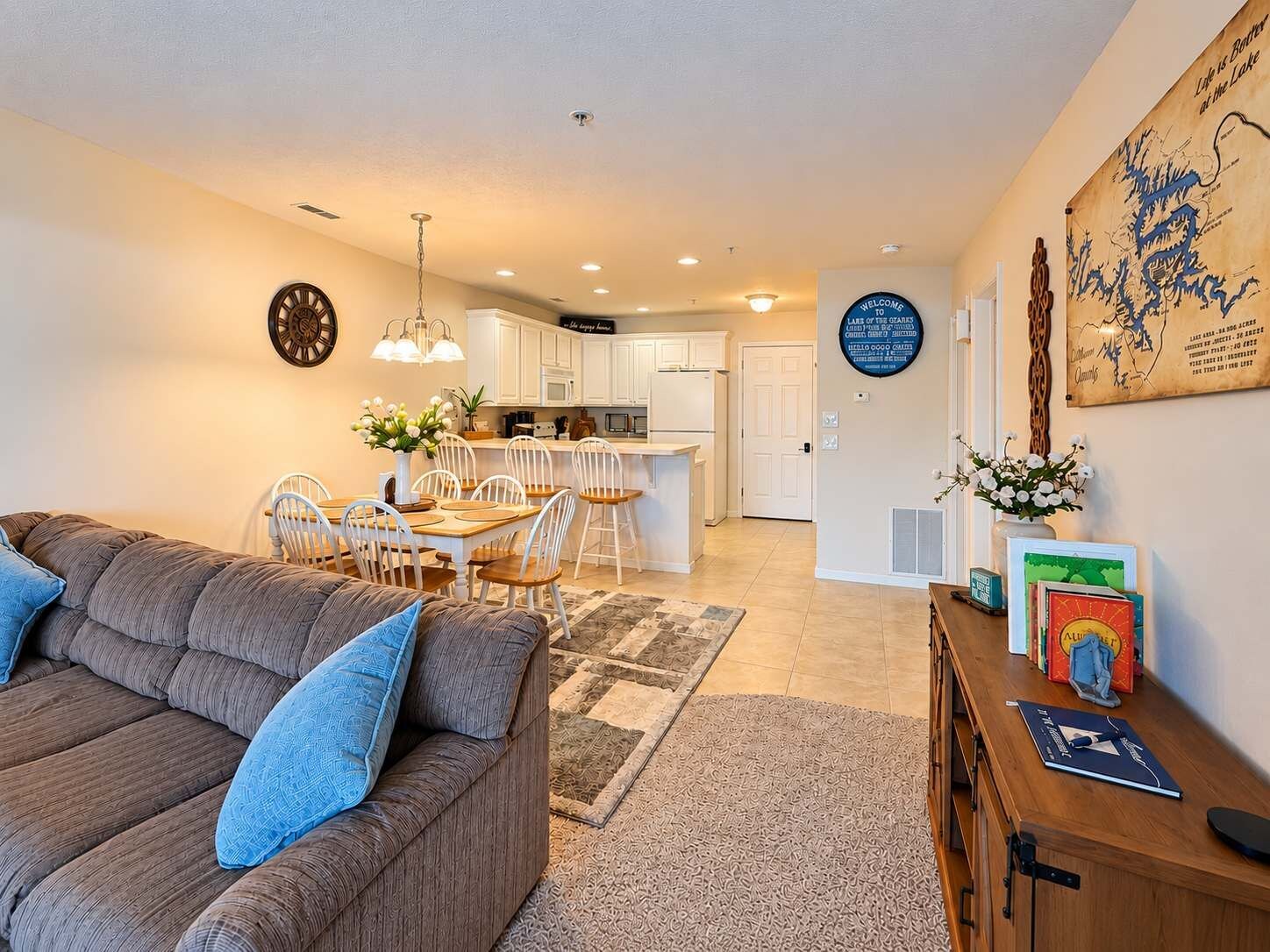 Una sala de estar moderna con sofá y sillones, una cocina con muebles blancos y un comedor con mesa y sillas.