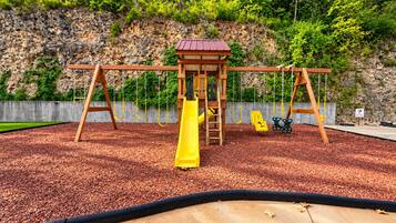 Un patio de juegos con tobogán, columpios y estructura para escalar.