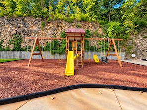 Ein Spielplatz mit Rutsche, Schaukeln und einer Kletteranlage.