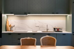 A modern kitchen with a marble backsplash, a stainless steel sink, and a dining area with two chairs. - Villa 'La Sapinière' with Air Conditioning, Pontaillac Beach within Walking Distance (Vaux-sur-Mer)
