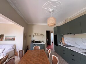 Ein Essbereich mit einem Holztisch und Stühlen, eine Küche mit grauen Schränken und eine Decke mit Sternenmuster.
