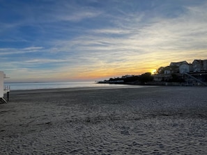 Una platja amb un capvespre, un edifici a la dreta i un cel serè.