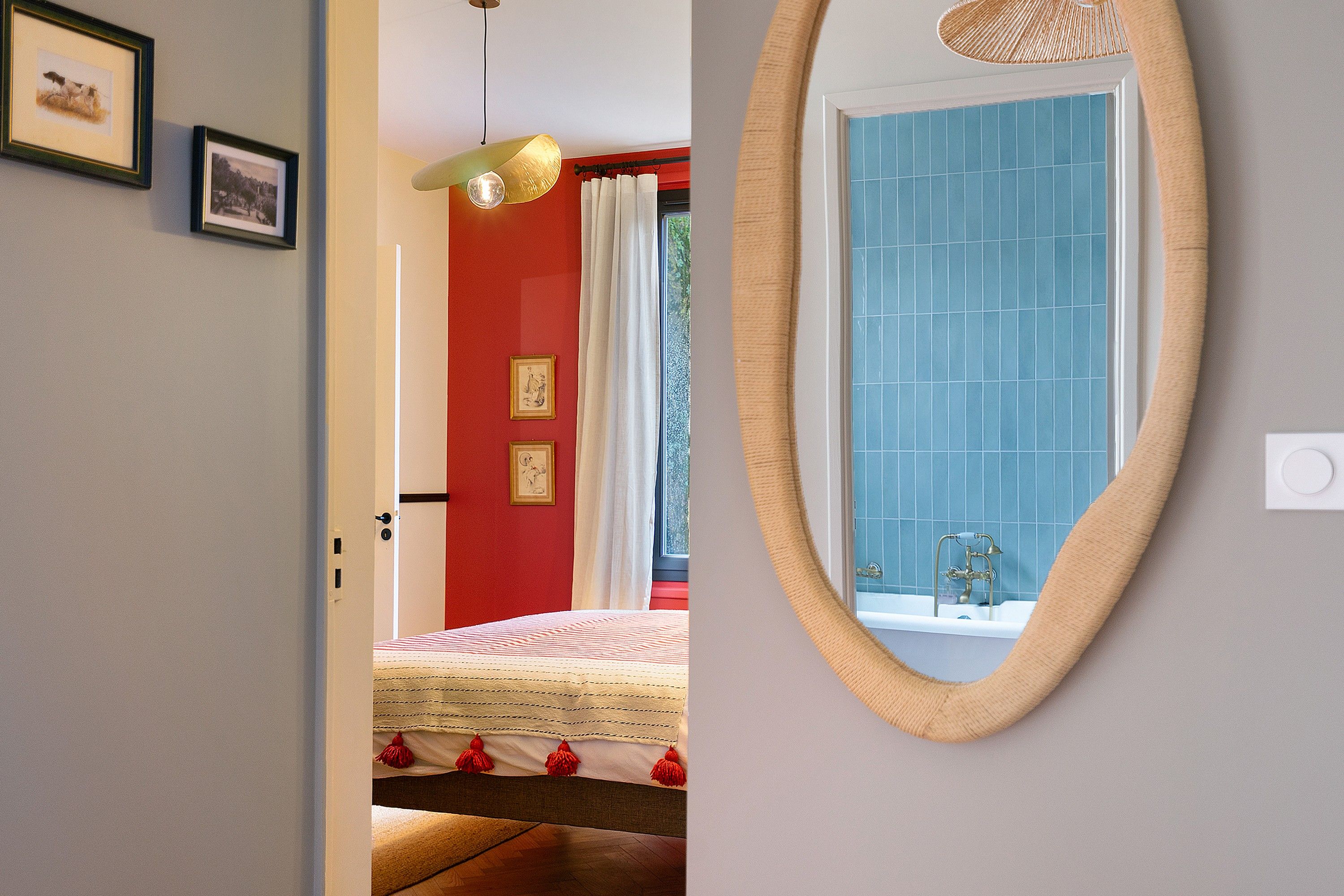 Un dormitorio con una cama, un espejo y una ventana con cortinas.