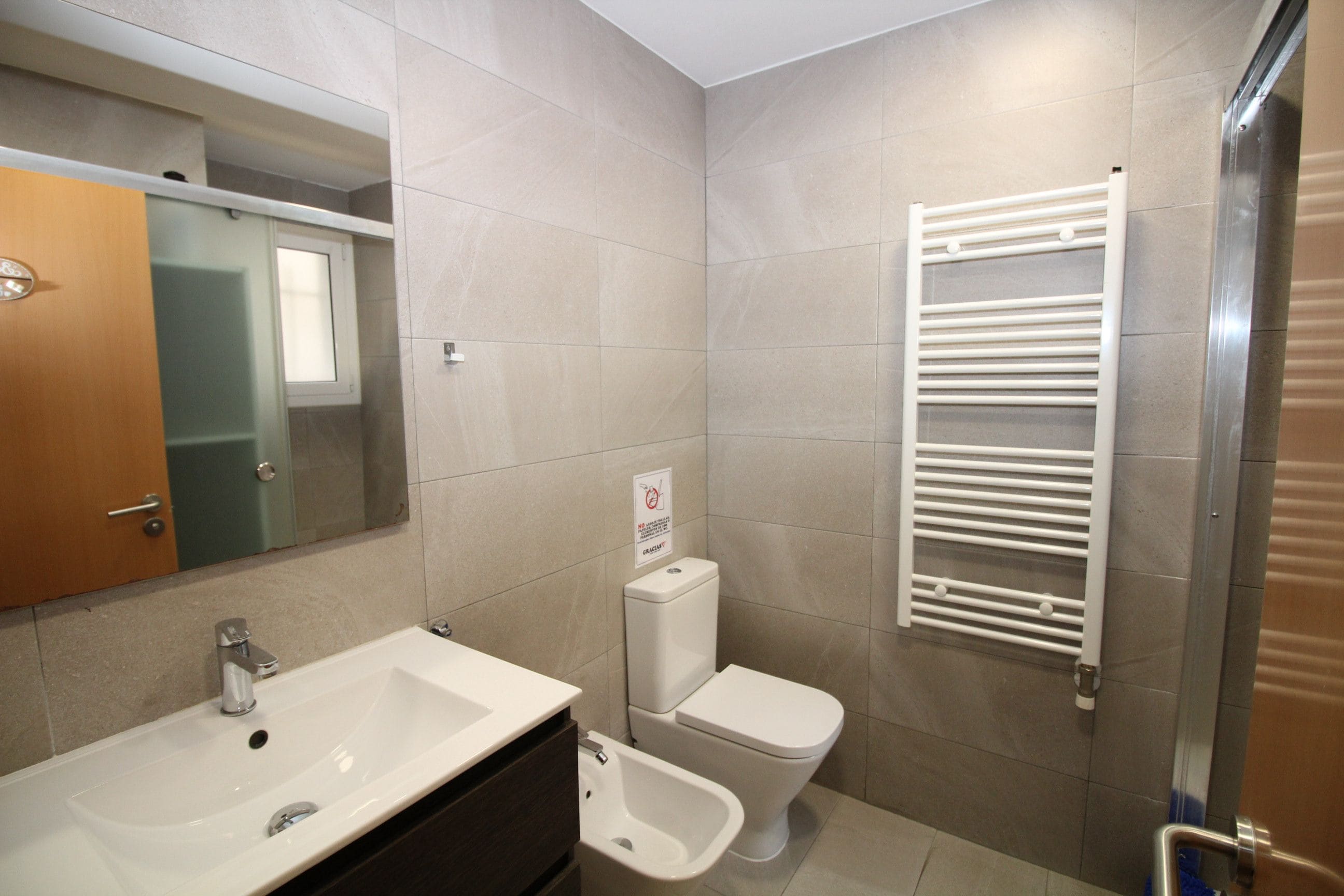 Un baño con lavamanos, inodoro y toallero.