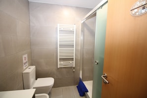 A bathroom with a toilet, a towel rack, and a shower area. - Habitaciones en Bonito Toledo (Madrid)
