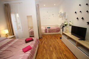A hotel room with two beds, a TV, a mirror, and a wall with butterfly decorations. - Habitaciones en Bonito Toledo (Madrid)