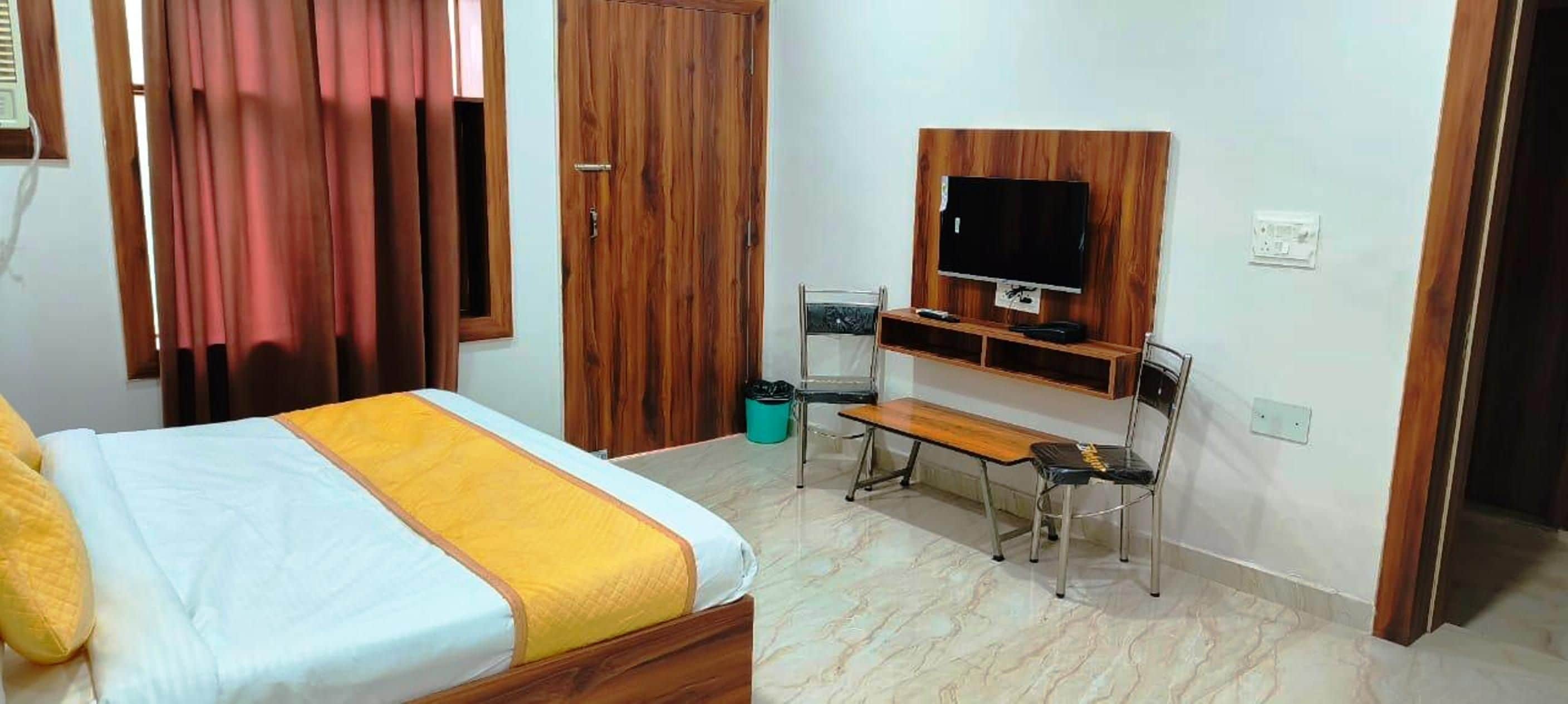 A hotel room with a bed, a desk, a chair, a television, and a wardrobe.