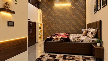 Un dormitorio con cama, mesitas de noche, ventilador de techo, iluminación empotrada, un papel tapiz estampado y suelo de mármol.