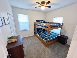 A bunk bed room with a ceiling fan, a desk with a lamp, and a window with blinds. - The Blue Cottage- 3BR Family Retreat on Lake Granbury, Gated, Community Pool (Granbury)