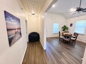 Ein Zimmer mit Essbereich, einem Sitzsack, einem Deckenventilator und einem Bild an der Wand.