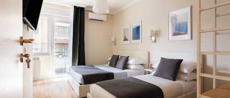 A hotel room with two beds, a TV, an air conditioning unit, and artwork on the walls.