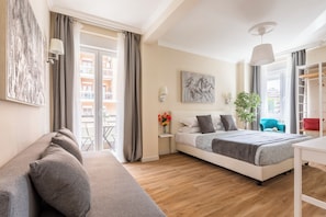 Une chambre d’hôtel avec un lit, un canapé, un bureau et une vue sur l’extérieur.