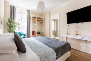 Une chambre à coucher avec un lit, une table de chevet, une télévision, une armoire et une plante.