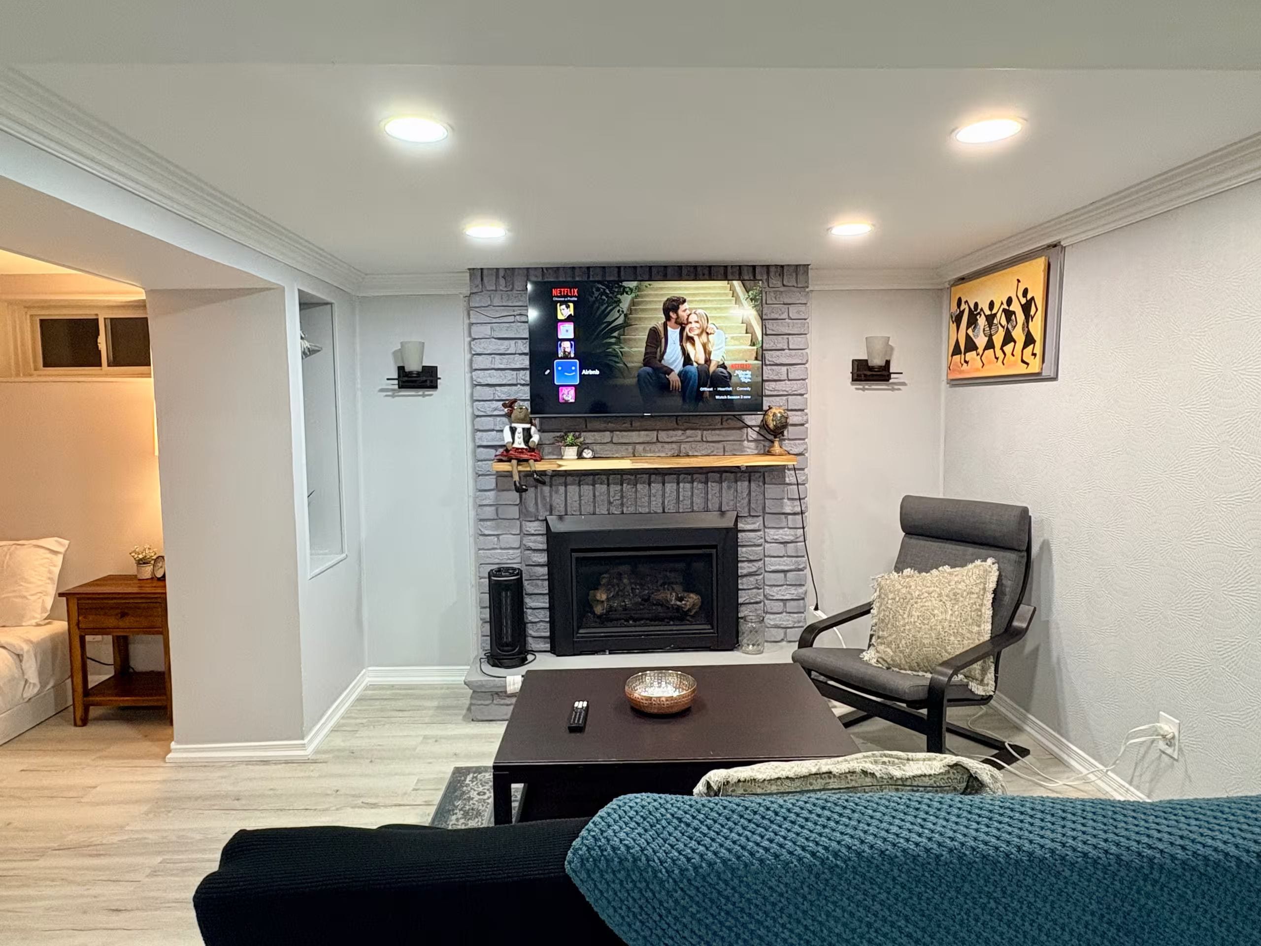 A living room with a fireplace, a television mounted above it, a sofa, a coffee table, and a chair.