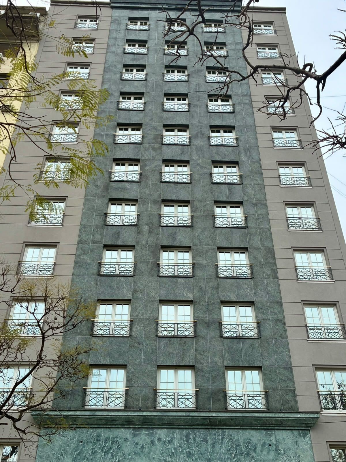 Un edificio de varios pisos con un estilo arquitectónico uniforme, con ventanas y balcones distribuidos de manera regular.