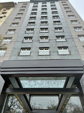 Un edificio de gran altura con múltiples balcones y una entrada moderna de vidrio.